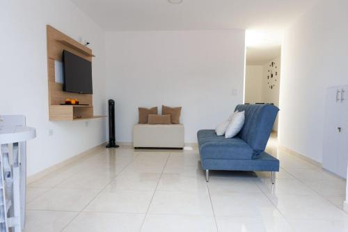 a living room with a blue chair and a tv at Apartamento 201 - a 5 minutos del centro de Pitalito in Pitalito