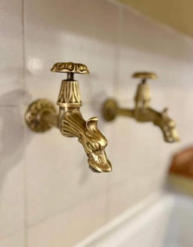 a gold bathroom faucet on a wall at NURAS - Gioberti Charme House in Alghero