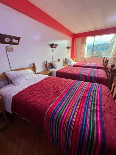 a hotel room with three beds with colorful blankets at Lhotse Hostel B&B in Huaraz