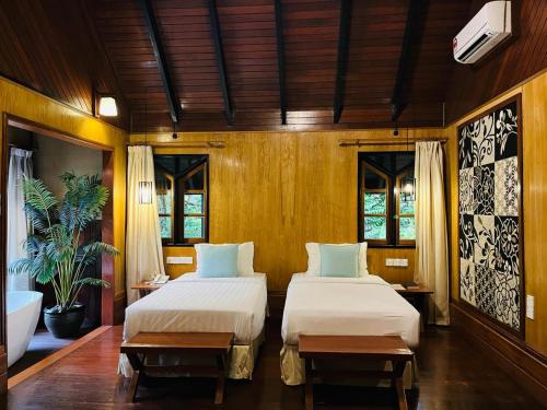 two beds in a room with wooden walls and windows at Sepilok Nature Lodge - Formerly known as Sepilok Nature Resort in Sandakan