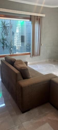 a brown couch in a living room with a window at Casa Flórida in Uberaba