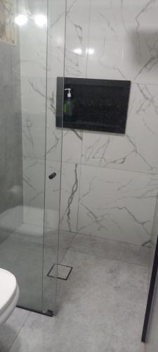 a bathroom with a glass shower with a toilet at Casa Flórida in Uberaba