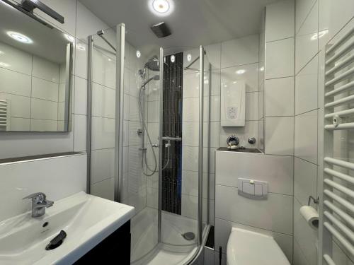 a white bathroom with a shower and a sink at Tief 10 Neptun mit Internet 607 in Wangerland