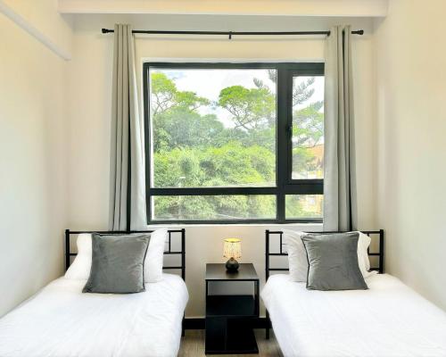 two beds in a room with a window at Neptune Luxe in Nairobi