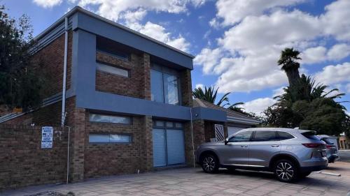 a silver car parked in front of a brick house at Cape one guest house in Welgelegen