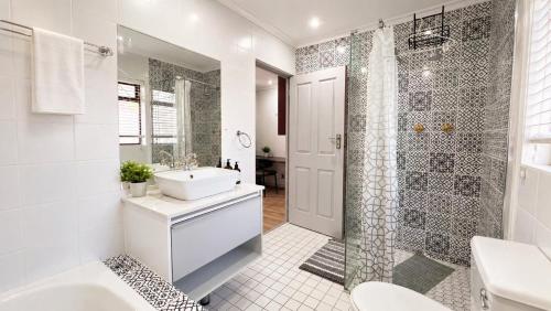 a white bathroom with a sink and a shower at Cape one guest house in Welgelegen