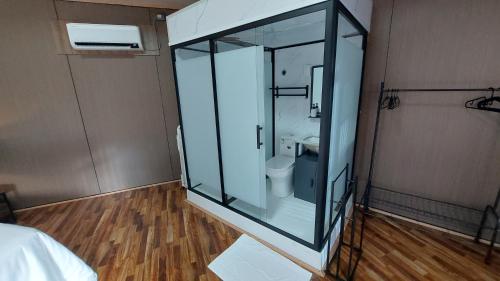 a glass shower in a room with a toilet at The Halfway Cafe-Dauin, Glamp2 - Grasshopper in Dauin