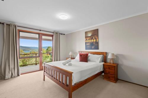 a bedroom with a bed and a large window at Winterwood 9 Camira Ave in Jindabyne