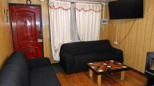a living room with a black couch and a red door at casa completa Balmaceda 77 in Concepción