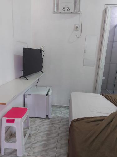 a room with two beds and a tv and a stool at Mini suíte Atitude no coração de Maragogi in Maragogi