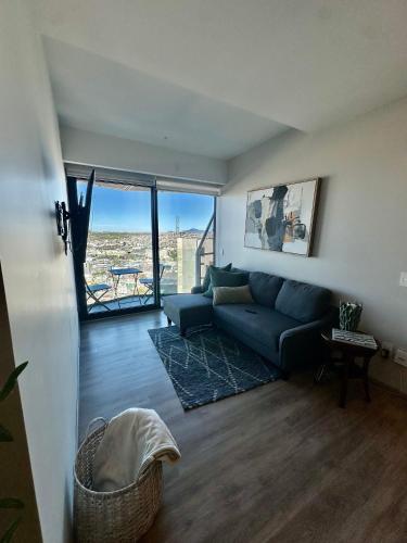 a living room with a blue couch and a large window at Exclusive Luxury Condo 2bd in Tijuana