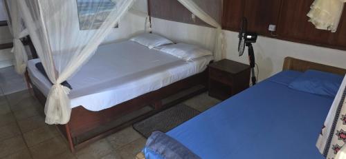 two beds in a small room with blue sheets at MAHAMBO BEACH hôtel in Mahambo