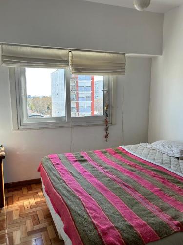 a bedroom with a large bed with a striped blanket at Cálido y luminoso hogar in Vicente López