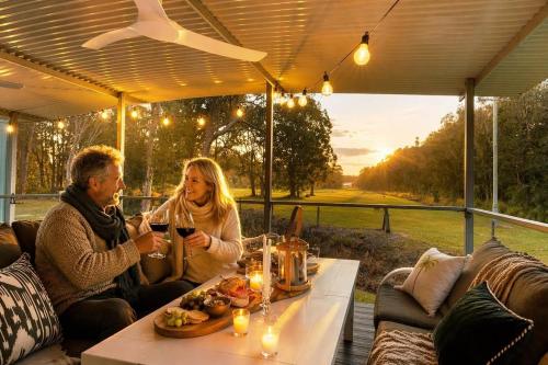 a man and woman sitting at a table with wine glasses at Leo's Beach Hideaway - Stylish Tiny Home in Arrawarra