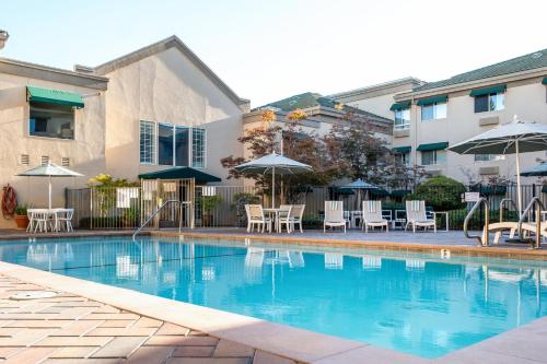 a swimming pool with tables and chairs and umbrellas at Holiday Inn Auburn by IHG in Auburn