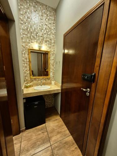 a bathroom with a sink and a wooden door at Recanto Luigi in Brotas