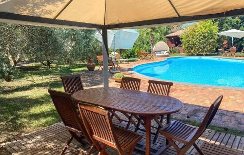 a wooden table with chairs and an umbrella next to a pool at Lovely Home In Tarquinia in Tarquinia