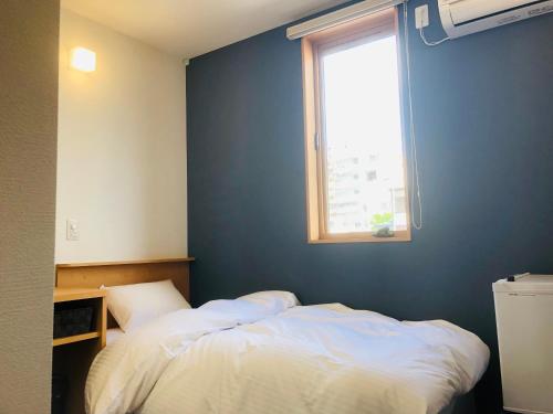 ein Schlafzimmer mit einem weißen Bett und einem Fenster in der Unterkunft からつホテルQueendom in Karatsu