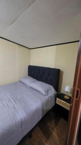 a small bedroom with a bed with a blue headboard at Hummingbird Morfus Lodge in Tilarán