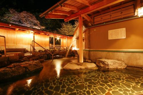 a pool of water with rocks and a building at Sun Urashima Yuki no Sato in Toba