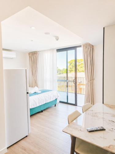 a bedroom with a bed and a table and a balcony at Auburn Studio, Entire Studio with Ensuite toilet and kitchen in Sydney