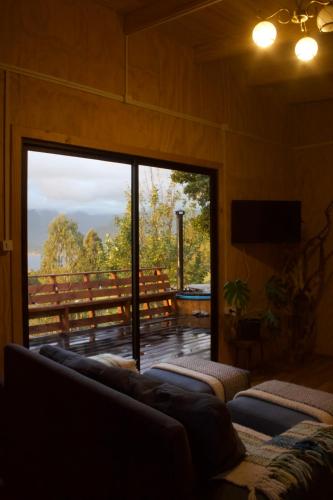 a living room with a large glass door to a deck at El Tilo Cabin - Hot Tub & Lake Ranco Views in Lago Ranco