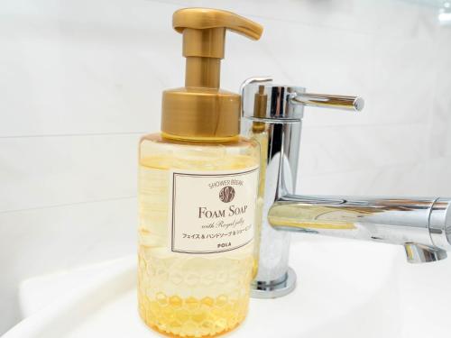 a bottle of liquid soap sitting next to a faucet at The BREAKFAST HOTEL PORTO Ishigakijima in Ishigaki Island