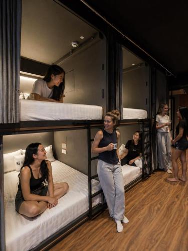 a group of people standing around in bunk beds at Straits Heritage Hostel in Singapore