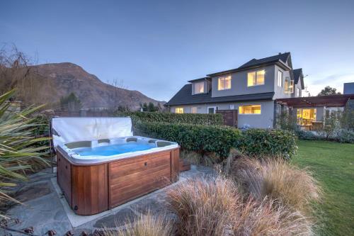 a hot tub in a yard next to a house at Queenstown Country Lodge in Queenstown
