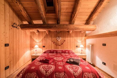 a bedroom with a red bed in a room with wooden walls at Vieilles Maisons D'Introd in Introd