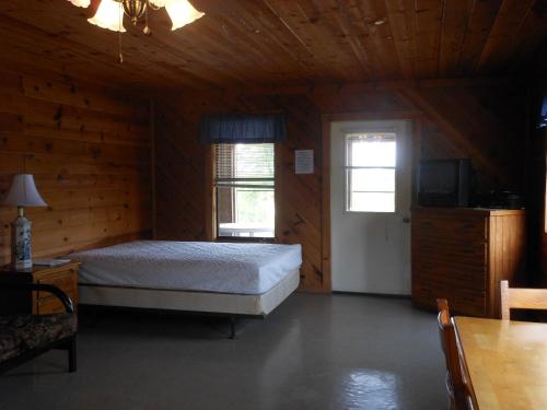 ein Schlafzimmer mit einem Bett und einem TV in einer Hütte in der Unterkunft Bay Landing Camping Resort Cabin 14 in Bridgeport