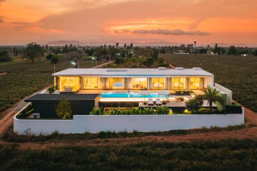 a house in a field with a sunset at Pinepilla Poolvilla Huahin in Hua Hin