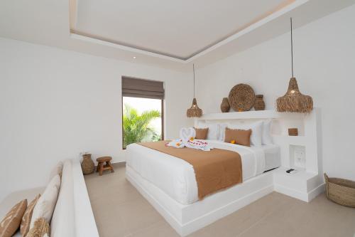 a white bedroom with a large bed and a window at Villa Camille - Private 1BR Oasis with Pool in Nyanyi Beach in Tanah Lot