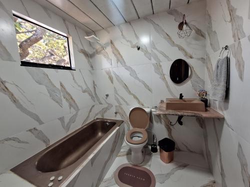 a bathroom with a tub and a toilet and a sink at Chalé da lagoa in Lagoa Santa