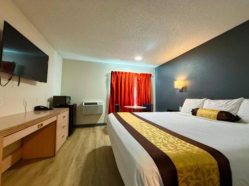 a hotel room with a large bed and a red curtain at Hermiston Inn & Suites in Hermiston
