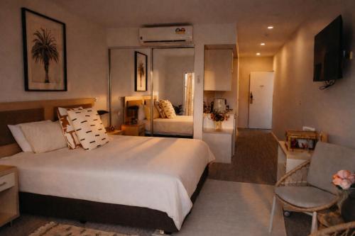 a hotel room with a large bed and a living room at Beautifully Restyled Studio Apartment - Oaks Pacific Blue - Sea Salt Escape in Salamander Bay