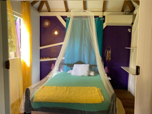 a bedroom with a bed with a canopy at Maison créole in Lamentin