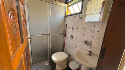 a small bathroom with a toilet and a sink at Chalés Água de Coco in Boicucanga