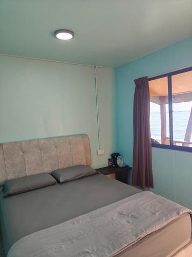 a bedroom with a large bed with a window at Permata Beach Chalet in Kampong Juara