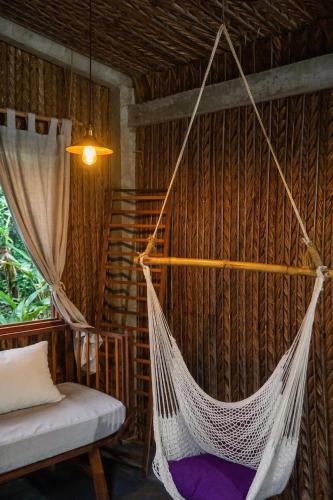 a hammock hanging in a room with a bed at Nông Trại Thảnh Thơi in Ben Tre