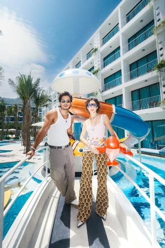 a man and woman standing on a cruise ship with a surfboard at Sugar Marina Hotel -POP- Kata Beach in Kata Beach
