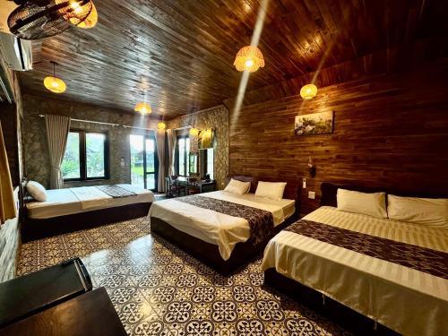 a bedroom with two beds and a wooden wall at Cham Trang An Retreat in Vũ Lâm