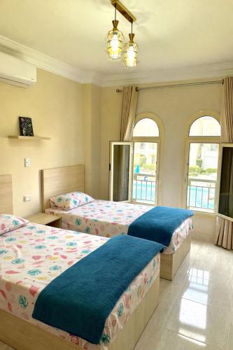 a bedroom with two beds and two windows at Lasirena Palm Beach Sokhna Chalet in Ain Sokhna