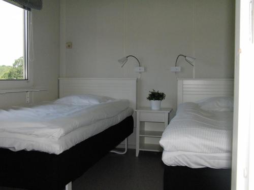 a bedroom with two beds and a window and two lamps at Vreta Kloster Golfklubb in Ljungsbro
