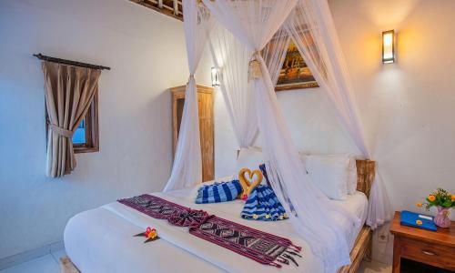 a bedroom with a white bed with a canopy at Svaha Private Villas Ceningan in Nusa Lembongan