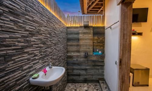 a bathroom with a sink and a stone wall at Svaha Private Villas Ceningan in Nusa Lembongan