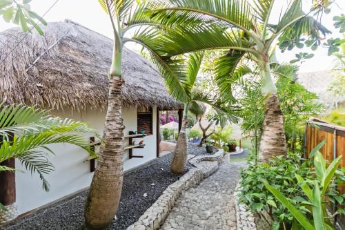a cottage with palm trees in front of it at Jabeki Bungalows Bingin Beach, Uluwatu in Uluwatu