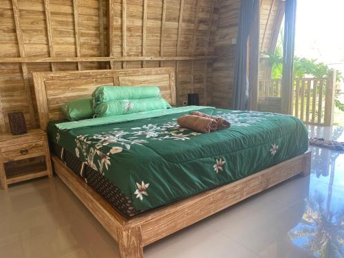 a bedroom with a bed with a green comforter at Sari Lumbung Bungalow in Penginuman
