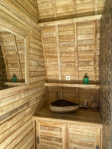 a bathroom with a wooden wall with a wooden sink at Sari Lumbung Bungalow in Penginuman
