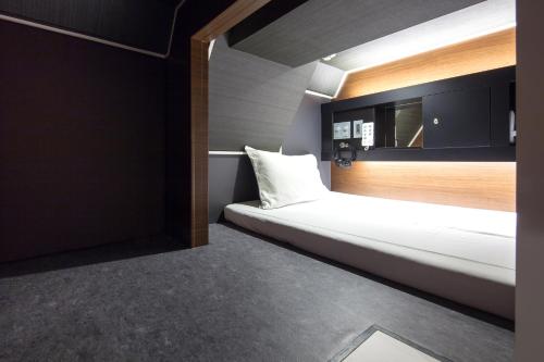 Cette petite chambre comprend un lit et un miroir. dans l'établissement commun SHIBUYA (Male Only), à Tokyo
